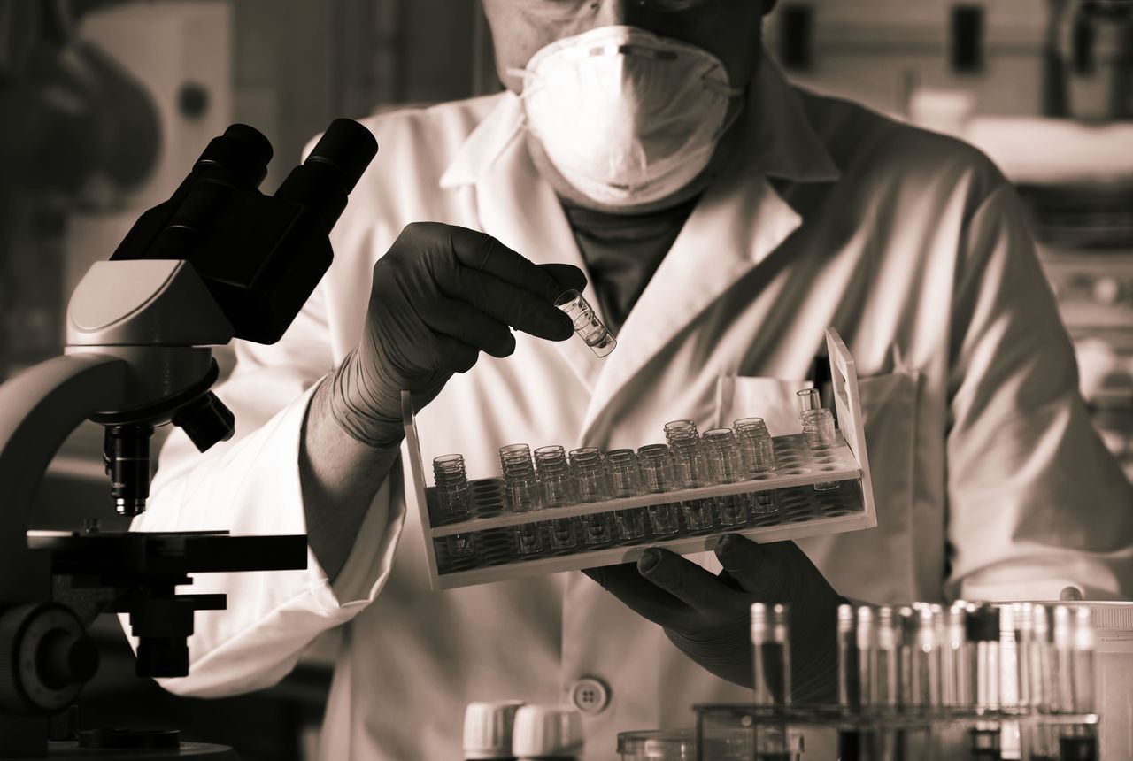 scientist working with sample for analysis in microscope in the lab / researcher holding tray with tube test for analysis in laboratory